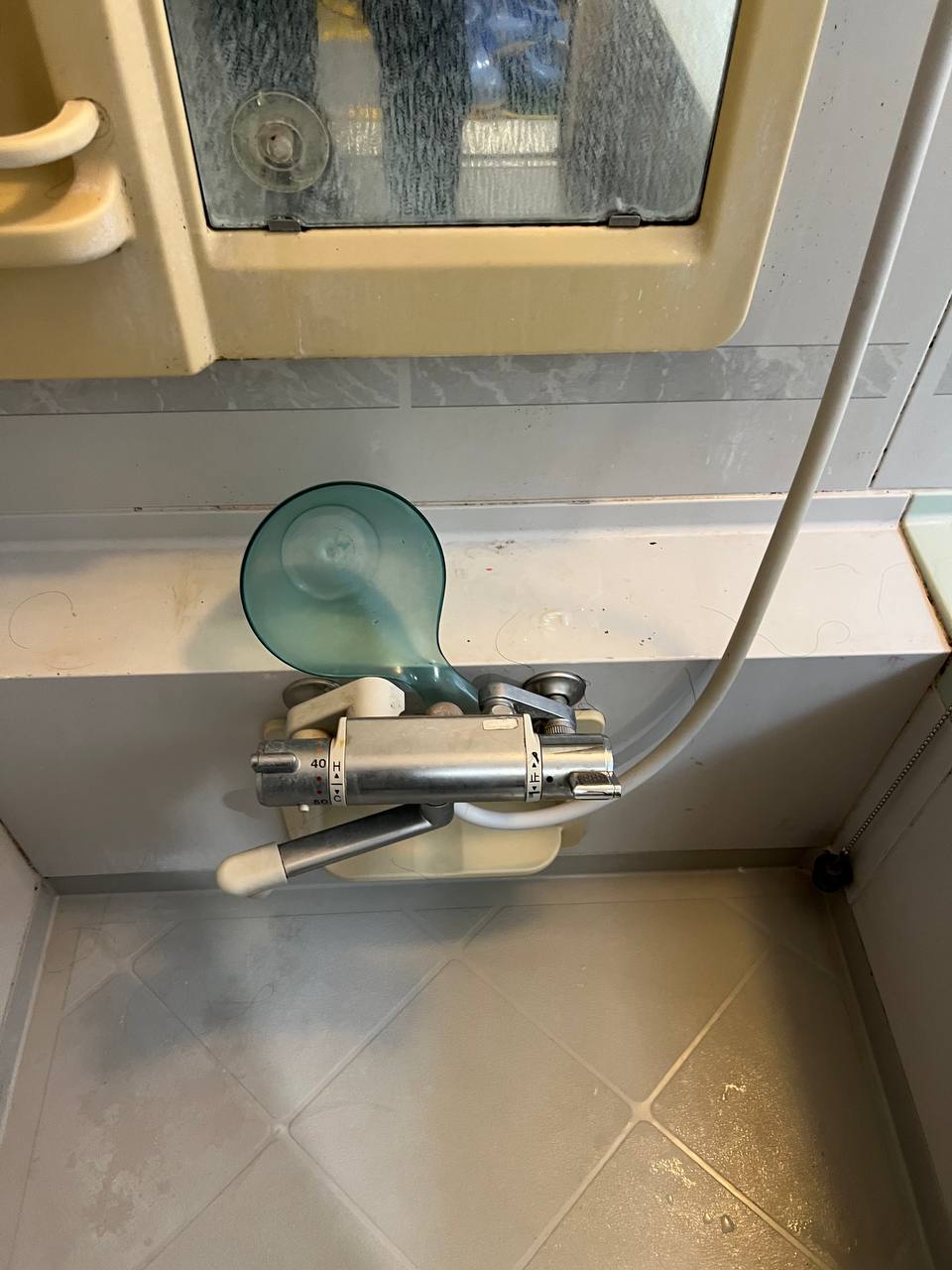 浴室の床に黒ずみ・石鹸カス汚れが広がり、蛇口ステンレス部分もくもりや水垢で曇っている清掃前の状態｜おそうじフレッシュ