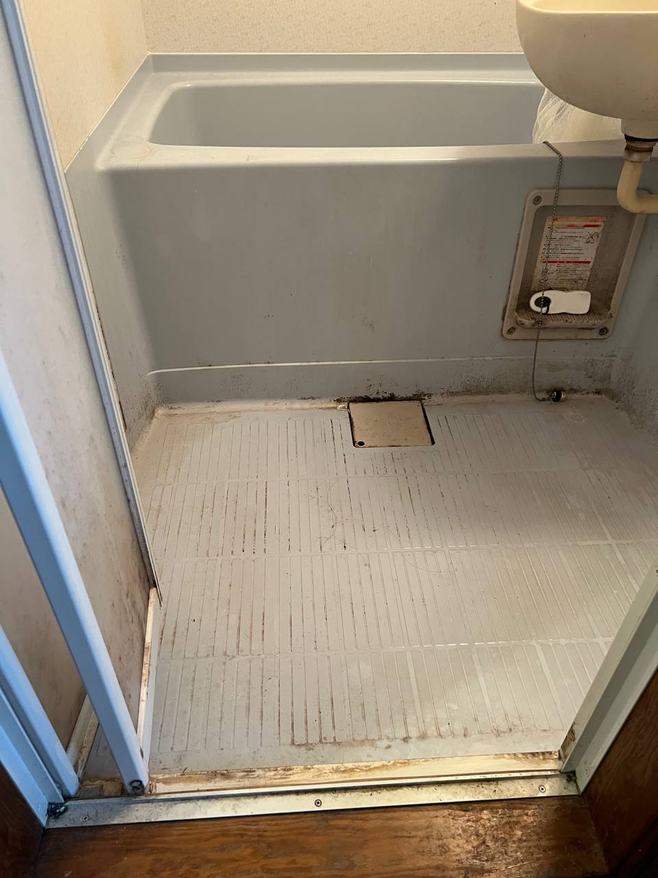 浴室床の黒ずみ・カビ・石鹸カス汚れが蓄積し、排水口まわりにも汚れが残っている清掃前の状態｜おそうじフレッシュ