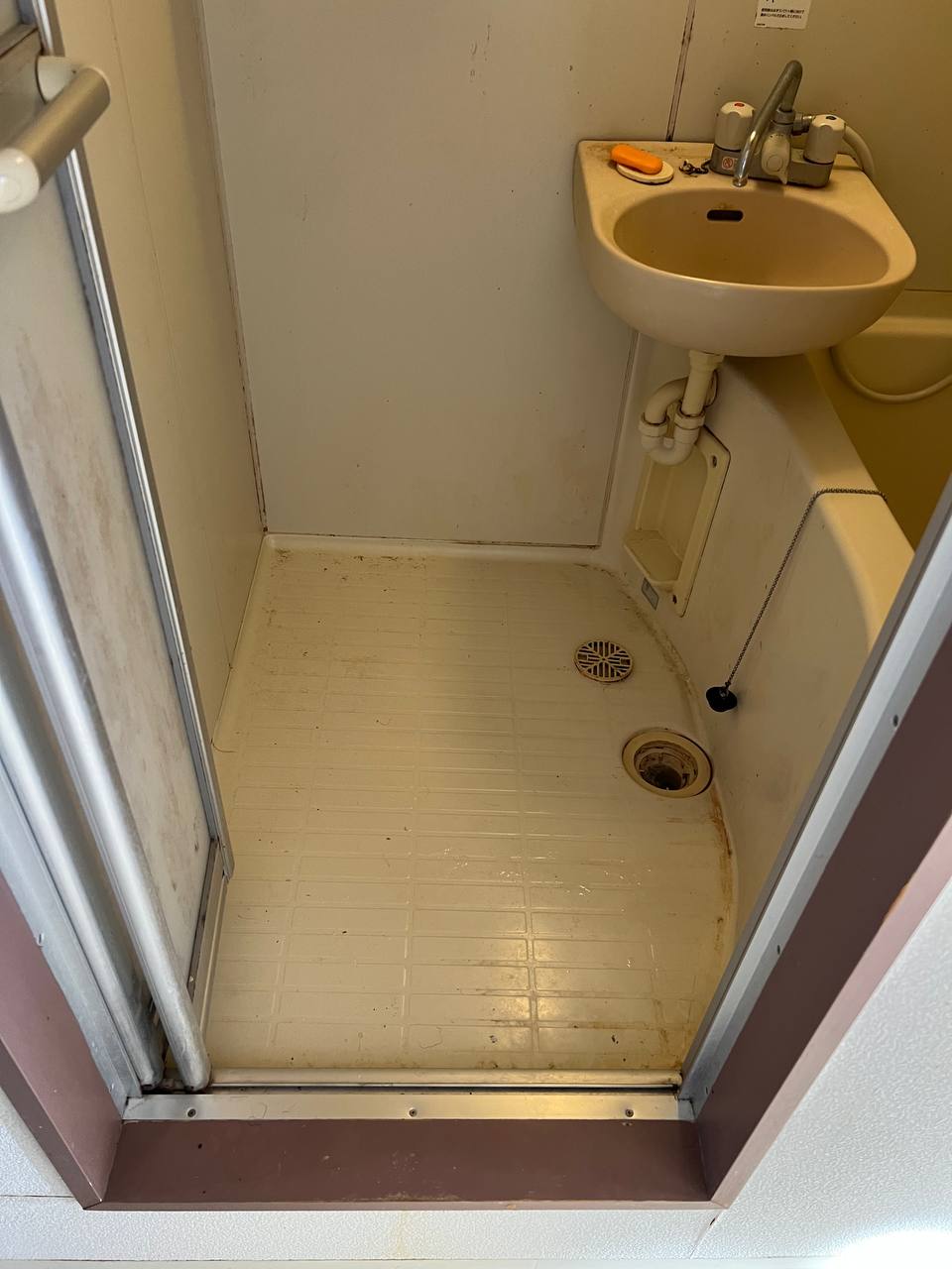 浴室床の黒ずみ・カビ・石鹸カス汚れが蓄積し、排水口まわりにも汚れが残っている清掃前の状態｜おそうじフレッシュ